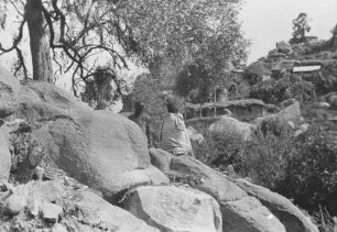 Koptenkloster Debre Bizen : Hütten des Koptenklosters Debre Bizen und zwei Männer in einer felsigen Landschaft