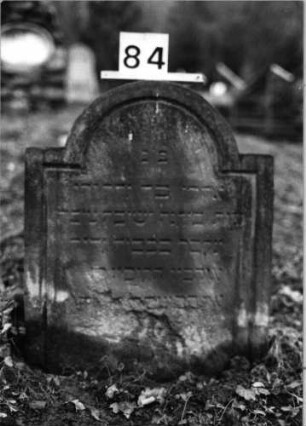 Grabstein 84 (Index: 100092882) Material: Sandstein Zustand: verwittert/Textverlust Maße HxBxT: 68x56x9 cm Beschreibung: Stele mit eingezogenem Rundbogenabschluß: Grabstein 84