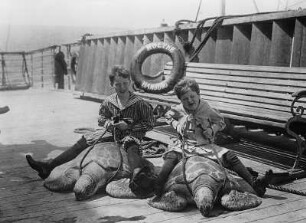 Hochseepassagierdampfer "Moltke" der Hapag Hamburg (Hamburg-Amerika-Linie). Sonnendeck mit zwei Kindern im Reitsitz auf Suppenschildkröten (Chelonia mydas)