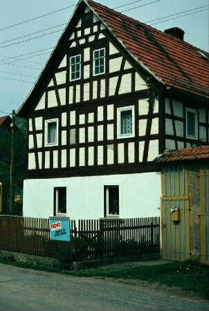 Giebel eines Bauernhauses, im OG eng stehendes Fachwerk, kleiner Garten vor dem EG
