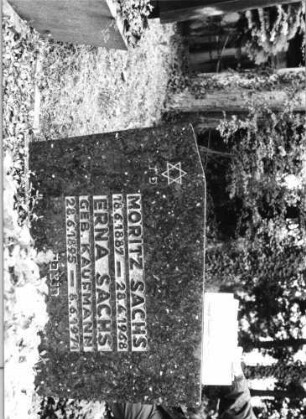 Grabstein 104 (Index: 100080280) Material: Granit Zustand: gut Maße HxBxT: 80x110x12 cm Beschreibung: sich nach oben verbreiternde breiet Stele, Sockel, nach links versetzter giebelartiger Abschluß Symbolik: Davidstern Besonderheit: Doppelgrab (für Eheleute?): Grabstein 104