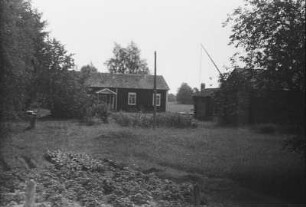 Siedlung : Blockhütten in einer norwegischen Siedlung. Davor ein Ziehbrunnen.