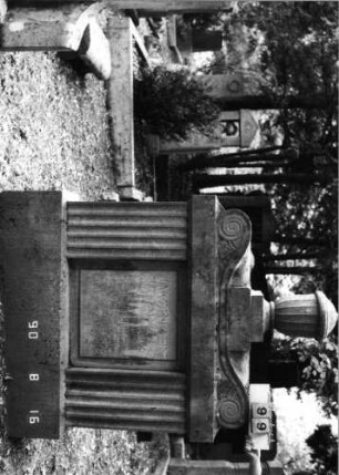 Grabstein 99 (Index: 99618523) Maße HxBxT: 183x140x30 cm Beschreibung: aufgesetzte Urne Symbolik: Verzierungen Besonderheit: Doppelgrab für Eheleute (mit Tochter?): Grabstein 99