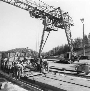 Gersdorf. VEB (B) Betonwerke Chemnitztal, Betriebsteil Betonwerke Gersdorf. Herstellung von Betonplatten. Arbeiter beim Glätten der Platten. Blick gegen den Brückenkran (Teilansicht)