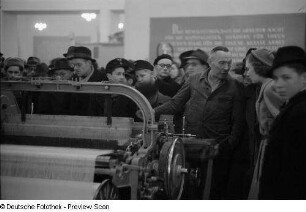 Messebesucher vor einer Textilmaschine