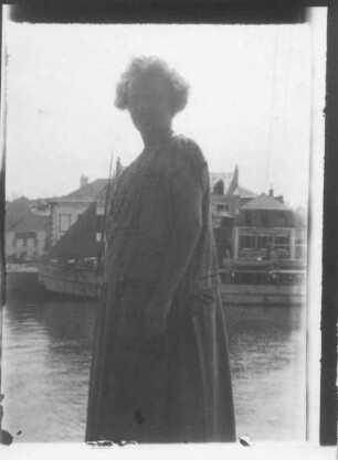 Die Bildhauerin Etha Richter im Sommerkleid auf dem Kai in einem Hafen
