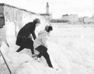 Winterurlauber an der zugefrorenen Küste der Ostsee in Warnemünde