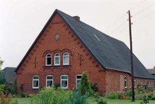 Seefeld 21: giebelständiges Bauernhaus aus Backstein: Straßenfront Wohntrakt: oben Rundbogenfenster und Backsteinzier, unter Ortgang steigender Treppenfries, darunter Medaillon mit Jahreszahl 1875: Traufseite, vorne Wohntrakt, Mitte Sprung, hinten Wirtschaftstrakt: Vorgarten, Telefonmast