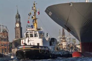 Hamburger Hafen, der Hafen-Schlepper Wilhelmine zieht einen Ozeanriesen. Im Hintergrund der Michel und mehrere Grosssegler. 07.2016