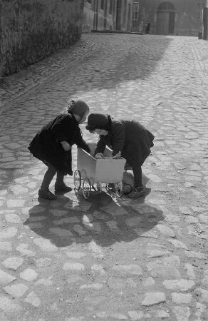 Zwei spielende Mädchen mit einem Puppenwagen