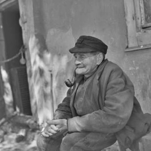 Bauer raucht Pfeife vor seinem Haus in Burg-Kauper. : Bur kuri trubku před swojim statokom w Kupaŕskich Bórkowach.