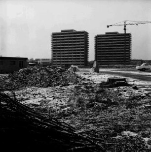 Poggenseer Weg / Im Hölk: Ehmkenberg: hinten Mitte zwei Hochhäuser im Rohbau mit Gerüsten: rechts davor Baukran: davor unbebautes Gelände mit Erdhaufen, ziegelstapel und parkendem Pkw: links Flachdachhaus: dahinter Wohnblocks: hinten rechts Reihenhäuser: Winter: 19. Januar 1973