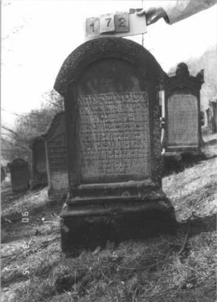 Grabstein 172 (Index: 99608857) Material: Sandstein Zustand: stärker verwittert Maße HxBxT: 116x62x23 cm Beschreibung: Stele, profilierter Sockel, überstehender Rundbogenabschluß Symbolik: Rundbogenfries Besonderheit: kulturhistorisch wertvoll / hist.-wiss. Gründe (Gemeindestellung): Grabstein 172