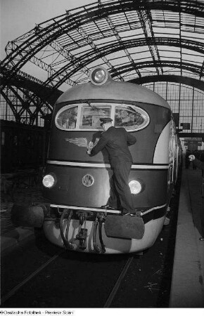 Bahnarbeiter beim Säubern des Logos der Deutschen Reichsbahn an einer Schnellzuglokomotive