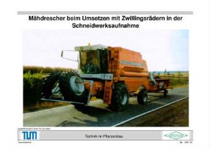 Mähdrescher beim Umsetzen mit Zwillingsrädern in der Schneidwerksaufnahme
