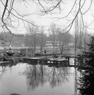Trave: Bürgerpark: Bau einer Travebrücke zwischen dem Konrad-Adenauer-Ring und dem Travestadion, links ein Krangerät, im Hintergrund das Vereinsheim, Blick Richtung Nordosten