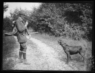 Nicht identifizierbare Gegend (Bayern (?)): Jäger mit Jagdhund auf einem Waldweg (Seitansicht)