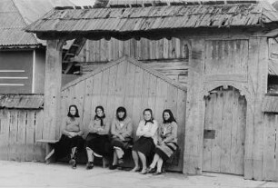 Frauen in Sonntagskleidung vor einem Hoftor