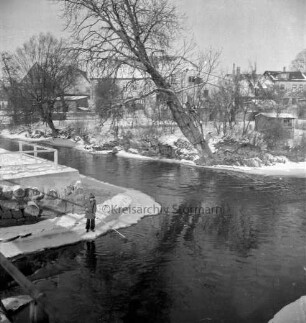 Trave: Beste: Zusammenfluss: Blick von der Fußgängerbrücke am Heiliggeistviertel: links Junge mit Stange am Wasser: hinten Häuser an der Lübecker Straße: Winter