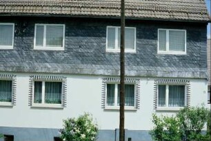 Traufseite eines Wohnhauses, OG verschiefert, Reste eines Ornamentes im OG