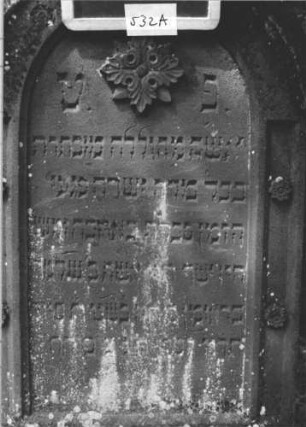 Grabstein 532 (Index: 99895470) Material: Sandstein Zustand: leicht bewachsen Maße HxBxT: 132x58x20 cm Beschreibung: Stele mit Rundbogenabschluss, kleiner Verdachung; Sockel Symbolik: Blüte: Grabstein 532A