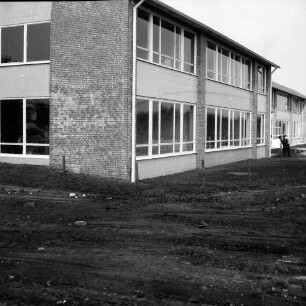 Realschule Harksheide: Fadens Tannen: Erweiterungsbau: vor Fertigstellung: vorn unbefestigte Außenanlage: hinten rechts Arbeiter mit Schaufel an Eingangstreppenstufe