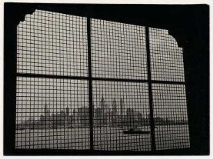 Blick durch vergitterte Fenster des Internierungsgebäudes von Ellis Island auf die Wolkenkratzer von New York
