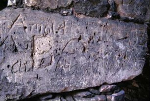 Steinblock von der Burgruine, von Besuchern mit Einkerbungen versehen