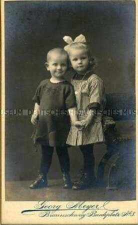Porträtfoto - Geschwister (Junge und Mädchen stehend und Hand haltend)