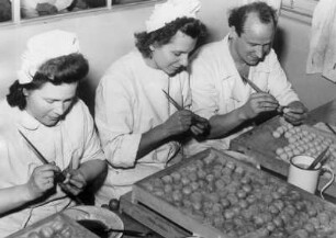 Mitarbeiter einer Süßwarenfabrik bemalen Marzipanfrüchte. Aufgenommen 1934