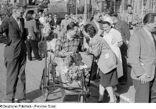 Porträt eines Mannes im Rollstuhl mit einem Blumenstrauß sowie weiteren Personen am Rand der Piste beim 6. Leipziger Stadtparkrennen