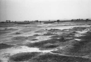 Landschaft : Einzelne Gebäude stehen auf einer freien Fläche in der Savanne.
