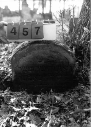 Grabstein 457 (Index: 100115567) Material: Sandstein Zustand: verwittert und im Boden versunken mit erheblichem Textverlust Maße HxBxT: 49x47x9 cm Beschreibung: Stele mit Rundbogenabschluß: Grabstein 457