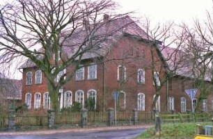 Dorfstraße 32: Bauernhaus aus Backstein: traufständiger Wohntrakt: Straßenfront mit Eingangsportal, Segmentbogen-Sprossenfenstern, Frontispiz mit ovalem Fenster, Fledermausgauben: Giebelseite Wohntrakt mit Blindfenstern: rechts rückwärtiger Wirtschaftstrakt an Straße Im Seybeck, Traufseite: vorne Hofmauer mit Holzzaun, Bäume