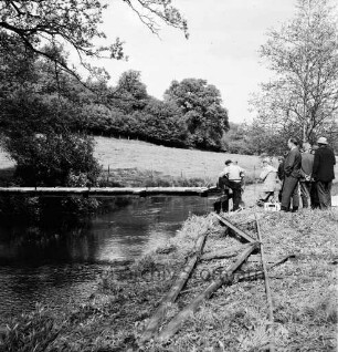 Sühlen: Trave: Wanderweg zwischen Sühlen und Bebensee (Kreis Segeberg): Fußgängerbrücke: Bau: Technisches Hilfswerk (THW) Bad Segeberg: rechts Gruppe von Helfern an Land beim Verlegen der letzten Holzbohlen: daneben Zuschauer: vorn rechts alte Brückenteile: hinten Bäume, Wiese und Wald