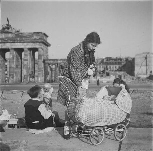Kinder mit Puppen und Puppenwagen vor der Ruine des Brandenburger Tores