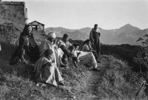 Versammlung : Eine Gruppe Männer der Kabylen sitzt an einem Hang vor dem Dorf.