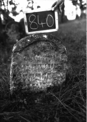 Grabstein 840 (Index: 100102919) Material: Sandstein Zustand: stark verwittert Maße HxBxT: 60x48x12 cm Beschreibung: Stele, unregelmäßiger Rundbogenabschluss, oben mit wulstigem Rand: Grabstein 840