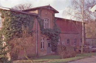 Altenfelde 3: giebelständiges Bauernhaus aus Backstein: Traufseite: links Wohntrakt, Kletterpflanzen: Mitte Risalit mit Eingangstür, Zwerchgiebel, Giebelzier: rechts Wirtschaftstrakt, Obergeschoss mit Verkleidung: davor Baumaterialien, Leiter: hinten rechts Schuppen