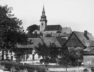 Elstra. Blick über Wohnhäuser zur Stadtkirche : Elstra. Blick über Wohnhäuser zur Stadtkirche St. Michaelis. Im Vordergrund Leiterwagen mit Stangenholz
