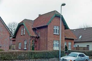 Ahrensfelde: Dorfstraße 31: traufständiges Wohnhaus aus Backstein: Straßenfront mit Quergiebel, links Eingangstür: Giebelseite: vorne Vorgartenmauer, Hecke
