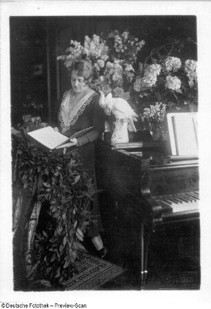 Elisabeth Rethberg mit Blumenarrangement und Geschenken : Porträt Elisabeth Rethberg aus feierlichem Anlaß mit Blumenarrangement und Geschenken in ihrer Wohnung. Fotografie von Ursula Richter, um 1928