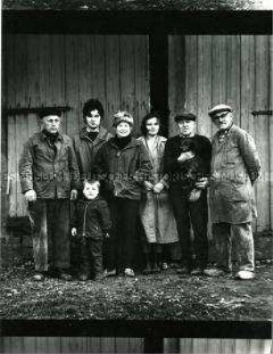 Ländliches Gruppenbild mit Kind und Dackel vor Scheunentor