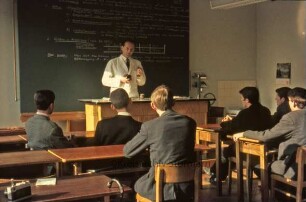 Kreisberufsschule [Ahrensburg]: Hermann-Löns-Straße: Innenaufnahme: Unterrichtsraum: Lehrer an Pult, Schüler an Schultischen, Wandtafel