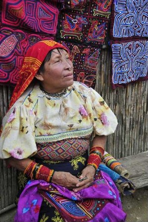 Kuna Yala - Kuna-Indianerfrau mit Molas : Eine Kuna-Indianerfrau sitzt vor ihrer Hütte, im Hintergrund selbst angefertigte textile Mola-Kunstwerke. Aufgenommen am 12. September 2011 auf einer der San Blas Inseln im autonomen Gebiet der Kuna-Indianer vor der Atlantikküste der Republik Panama