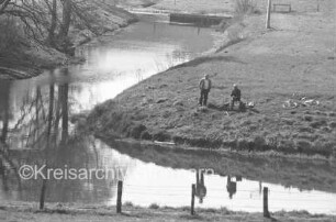 Trave: Kneeden: Angler auf Weide am Flußarm: im Vordergrund Weide mit Zaun: rechts Fahrrad: im Hintergrund Bäume und Steg