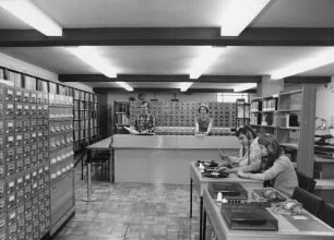 Dresden-Neustadt, Stauffenbergallee 9 (ehemalige Garnisonskirche). Sächsische Landesbibliothek, Außenstelle Phonothek, 1. Obergeschoß. Mitarbeiter im Benutzungsbereich Tonträger mit Ausleihtheke, Zettelkatalogen, Schallplatten- und Bücherregalen sowie Abhörtischen