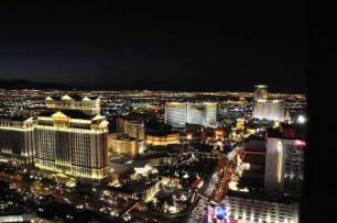 Nächtliches Las Vegas mit Caesars Palace Hotel (links) : Blick vom Nachbau des Pariser Eiffelturms am Las Vegas Boulevard auf das am Abend beleuchtete Las Vegas, aufgenommen am 8. August 2012