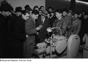 Besucher an einem Messestand mit Maschinen im Ausstellungspavillon von China