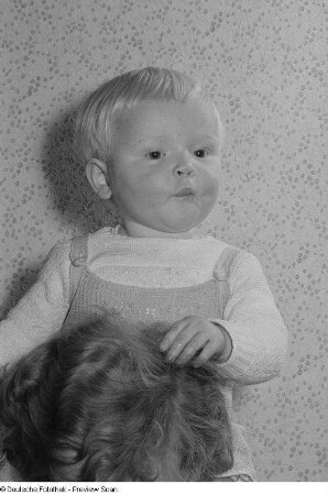 Portrait eines Kleinkindes auf den Schultern einer erwachsenen Person